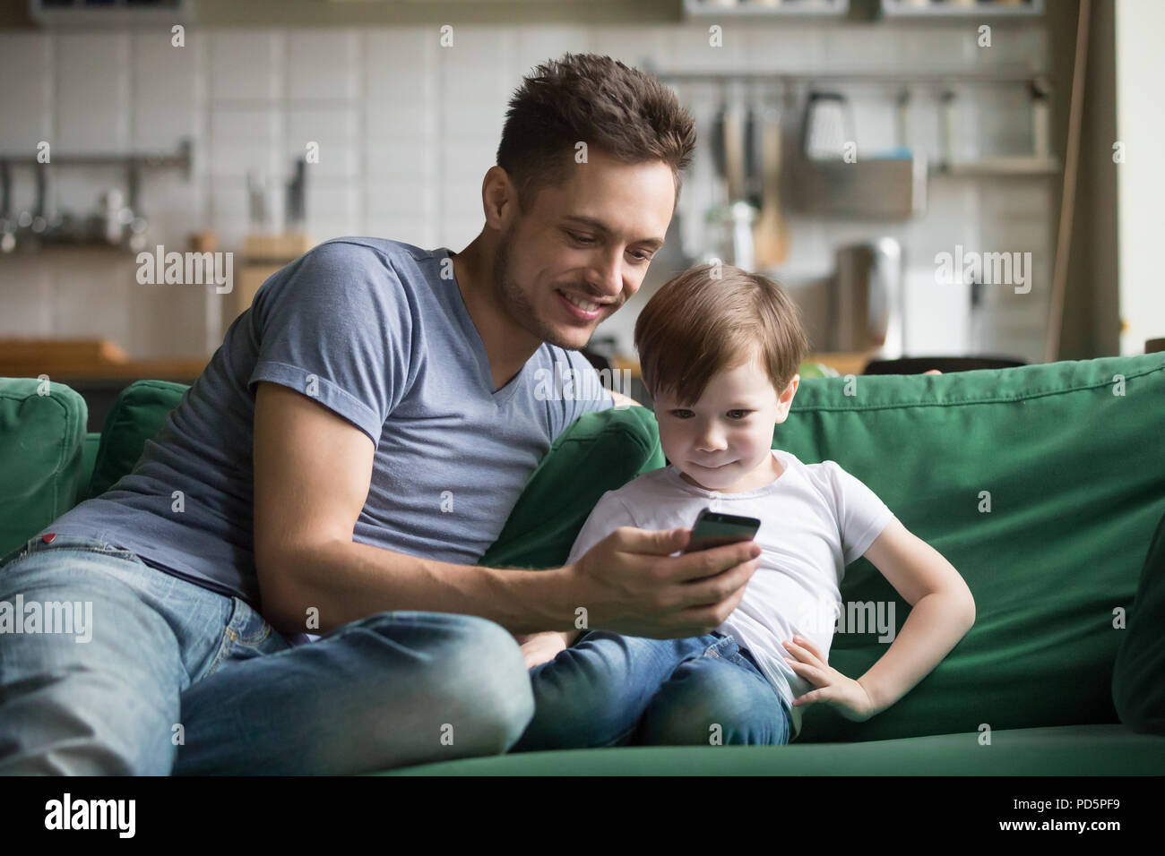 Smiling dad with kid son watching funny video on phone Stock Photo