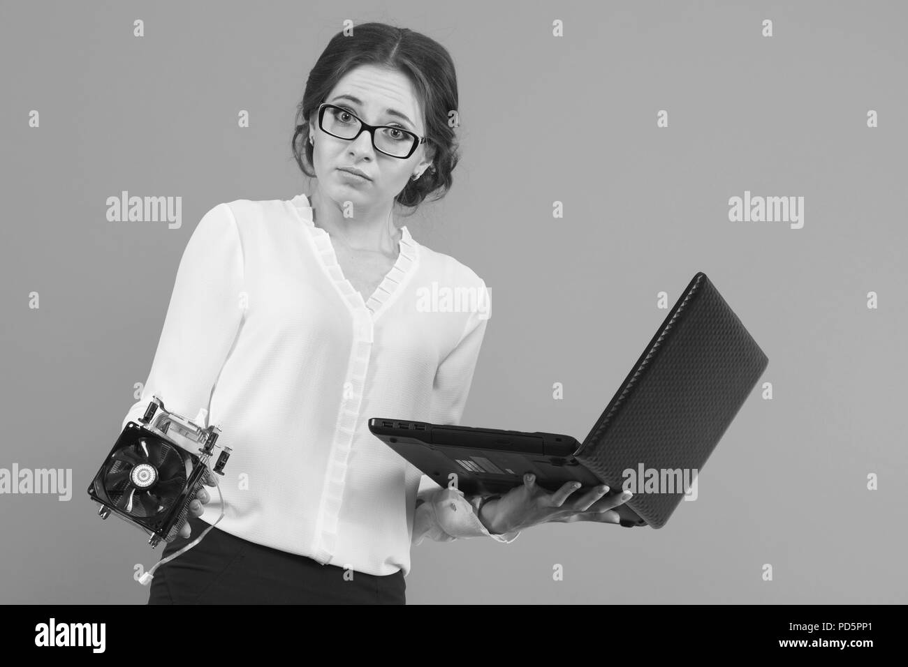 Portrait of confident beautiful puzzled confused young business woman with equipment computer parts in black and white Stock Photo