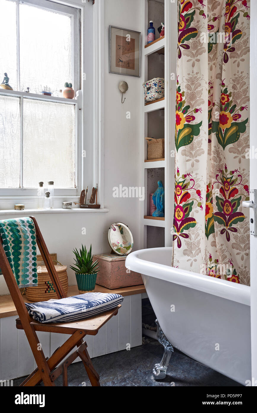 Brightly coloured shower curtain based on Swedish Kurbits folk art in bathroom with freestanding bath. Stock Photo