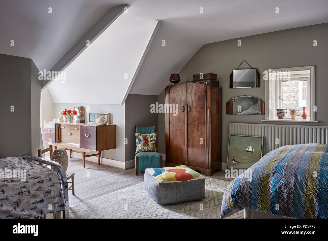 Attic bedroom painted in French Grey Dark by Little Greene. The floor cushion is from Maxine sutton and the wardobe is 1930s. Stock Photo