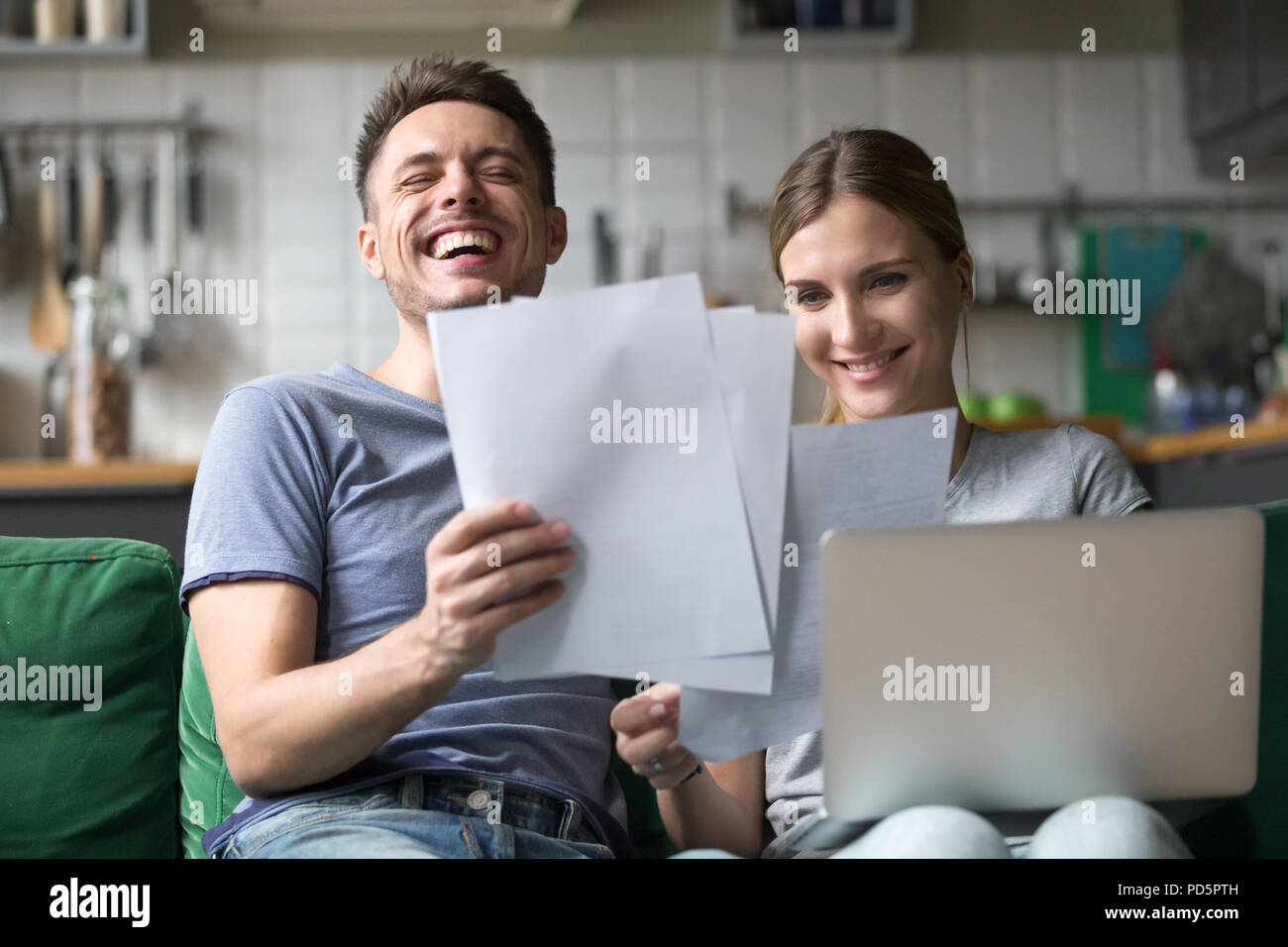 Happy couple laughing having fun with documents and laptop Stock Photo ...