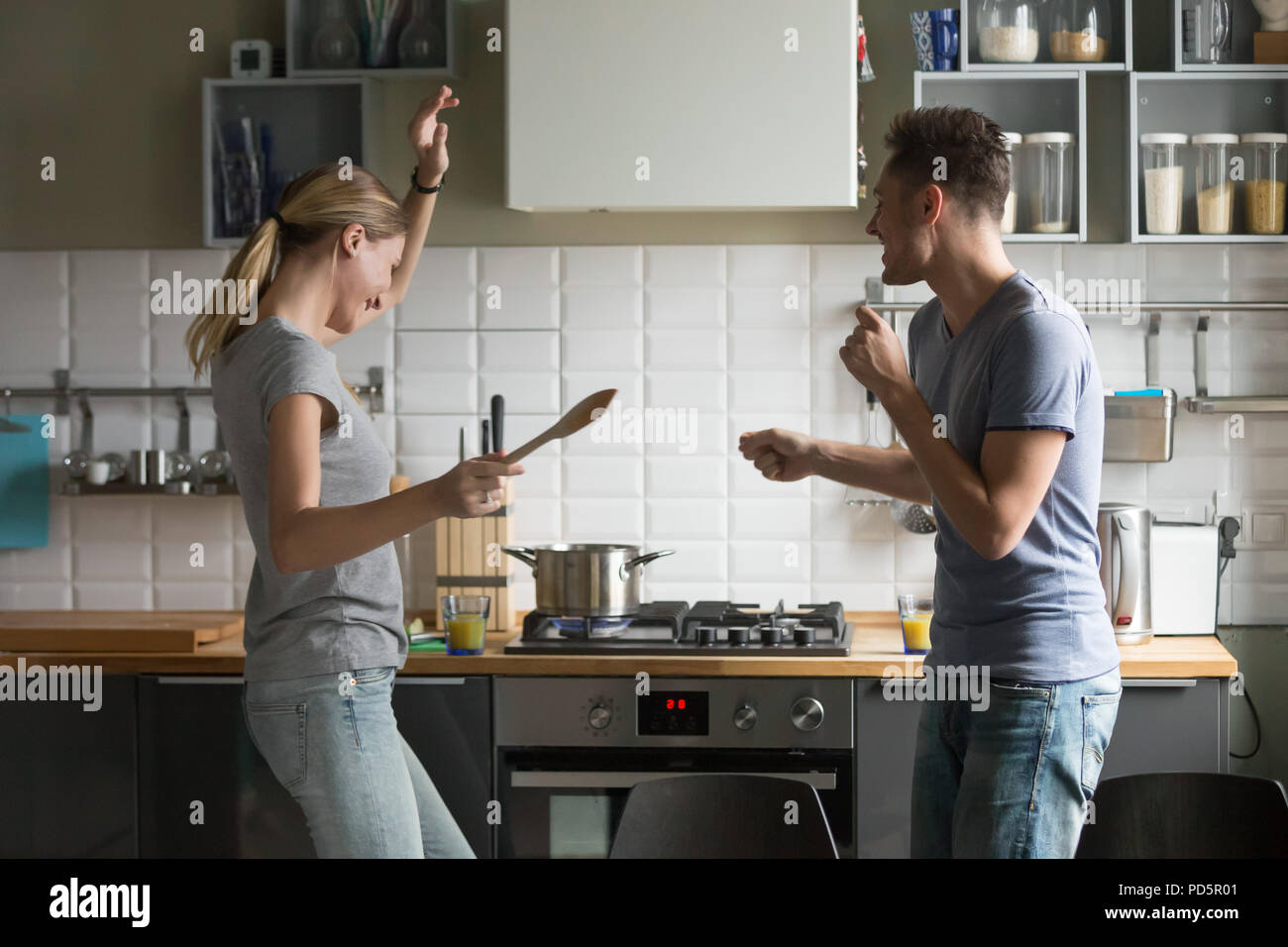 Funny young couple dancing together enjoying cooking in the kitc Stock Photo