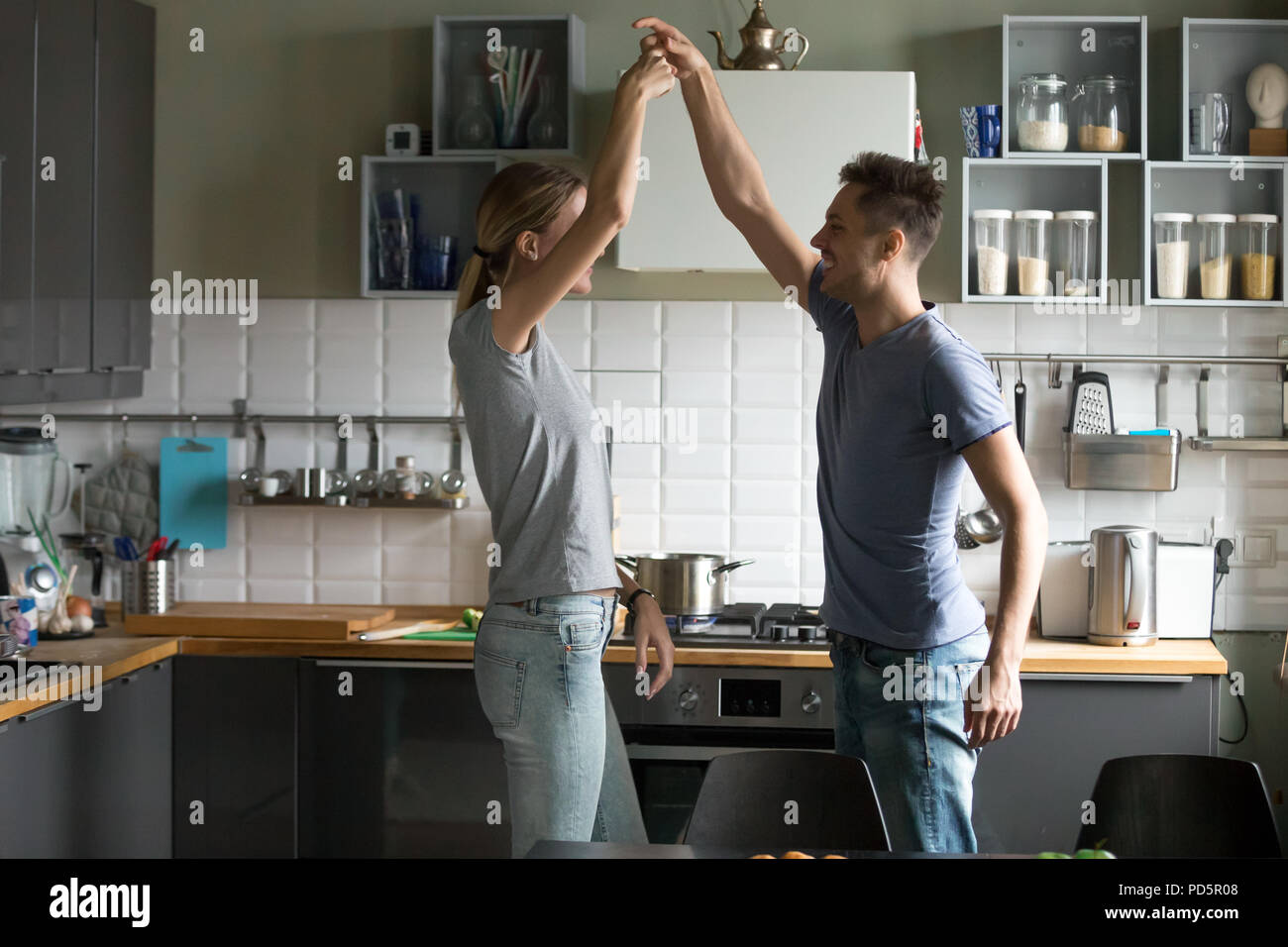 Happy romantic couple dancing in the kitchen while cooking toget Stock Photo