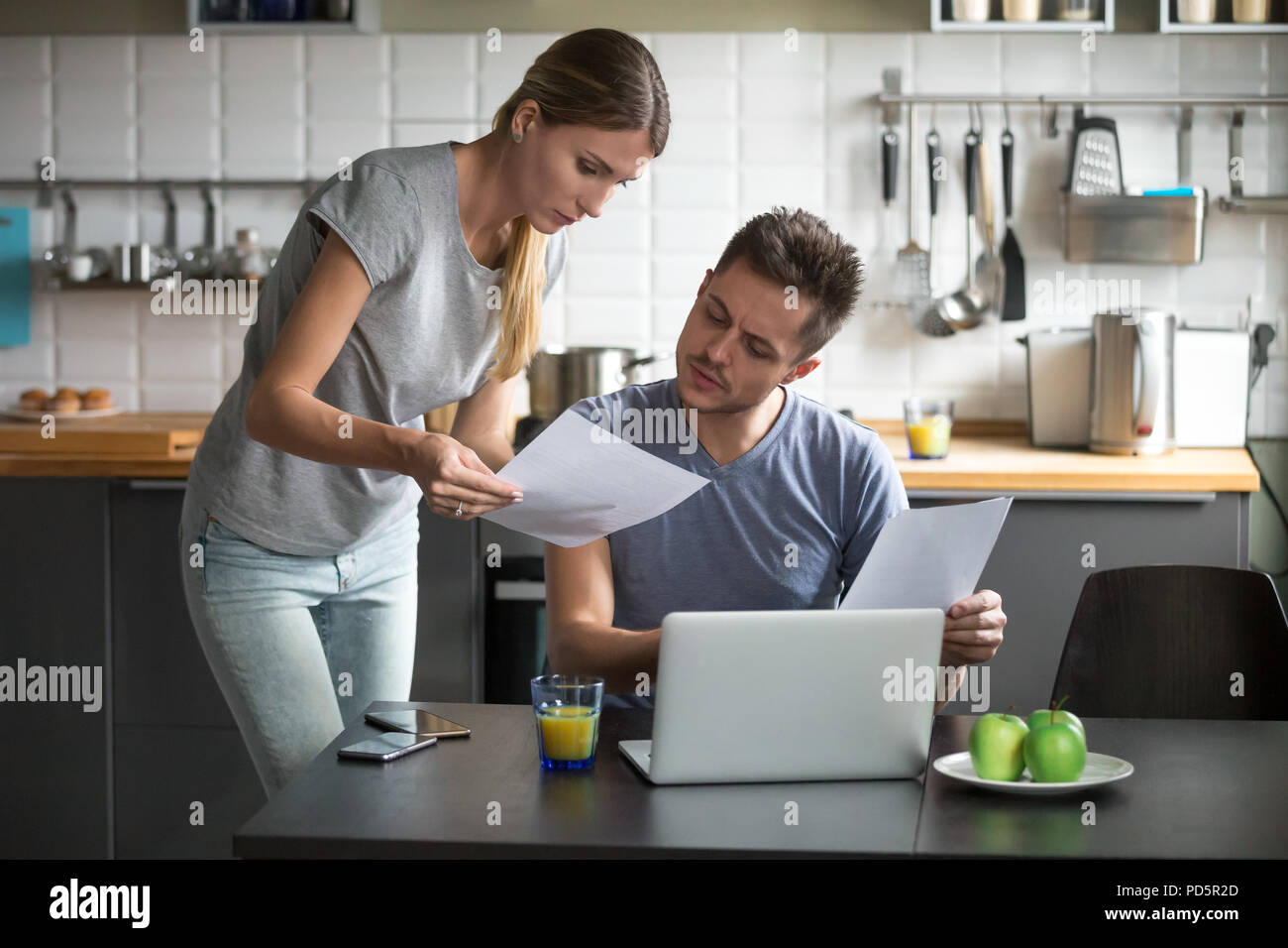Serious young couple worried discussing utility bills in the kit Stock Photo