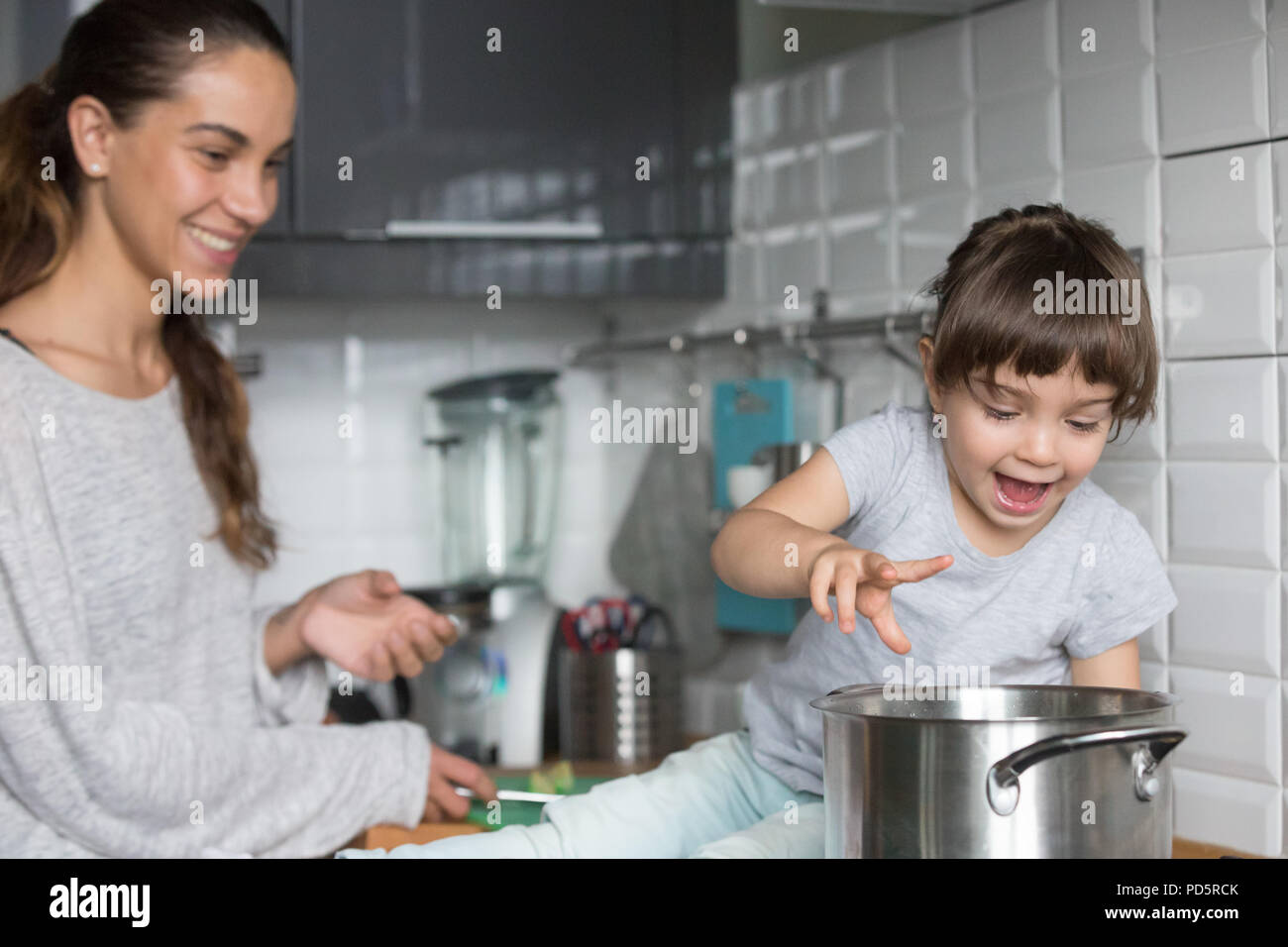 https://c8.alamy.com/comp/PD5RCK/curious-girl-playing-with-pot-cooking-with-mom-in-kitchen-PD5RCK.jpg