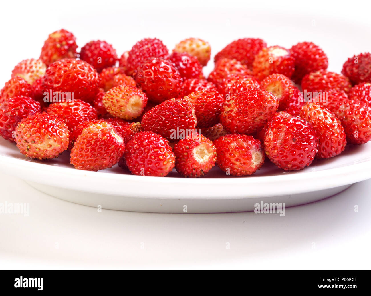 Wild strawberry in white plate and white background Stock Photo - Alamy