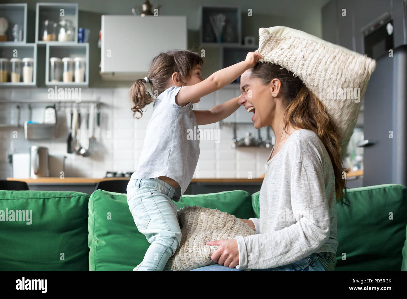 Mommy and kid daughter having pillow fight playing together Stock Photo