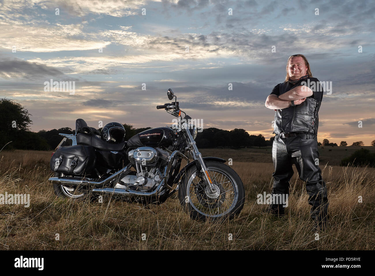 Leather clad biker posing for a photoshoot on his custom Harley ...