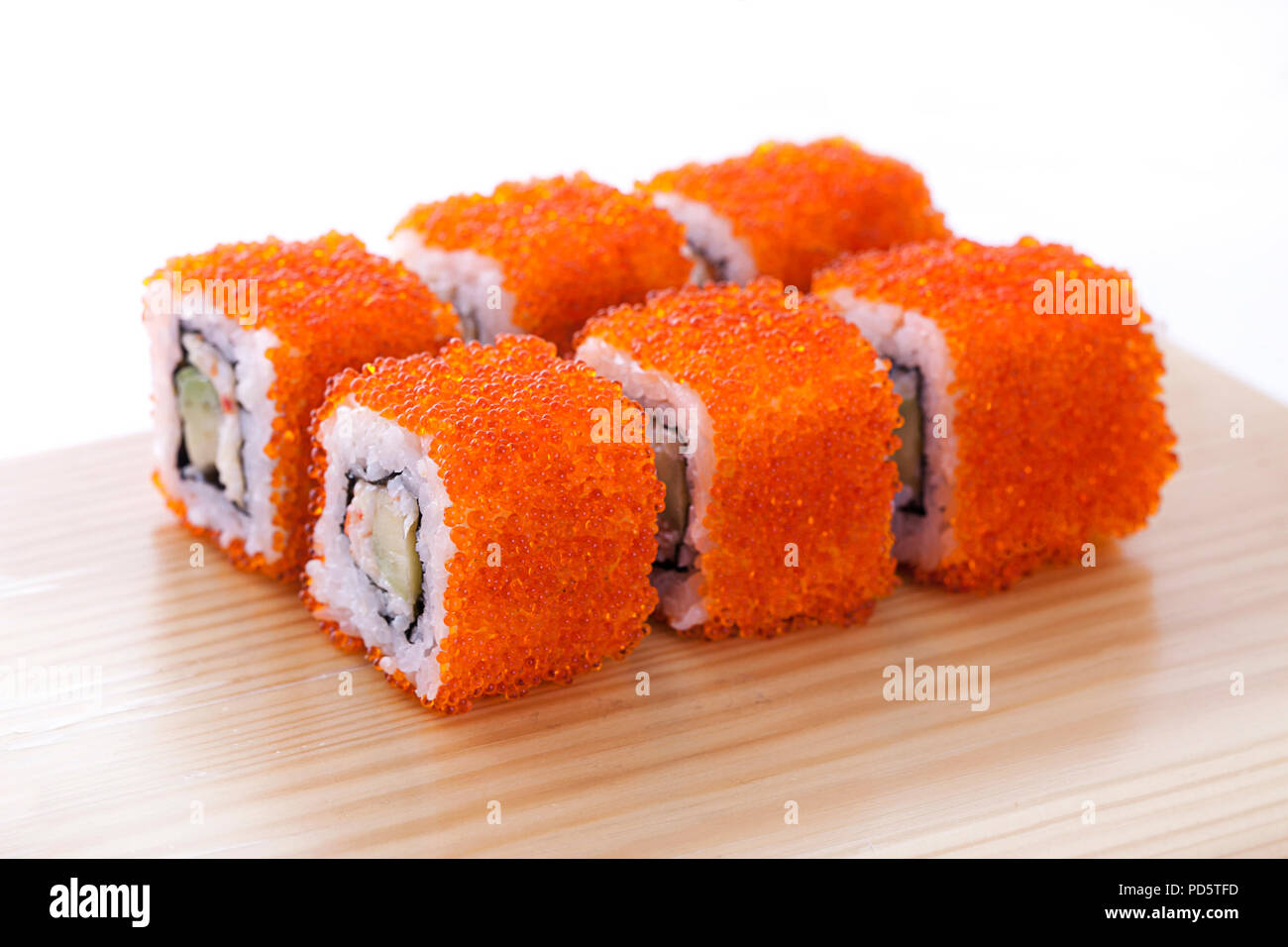 One set of California rolls covered orange tobiko or masago caviar on a  wooden board on a white background Stock Photo - Alamy
