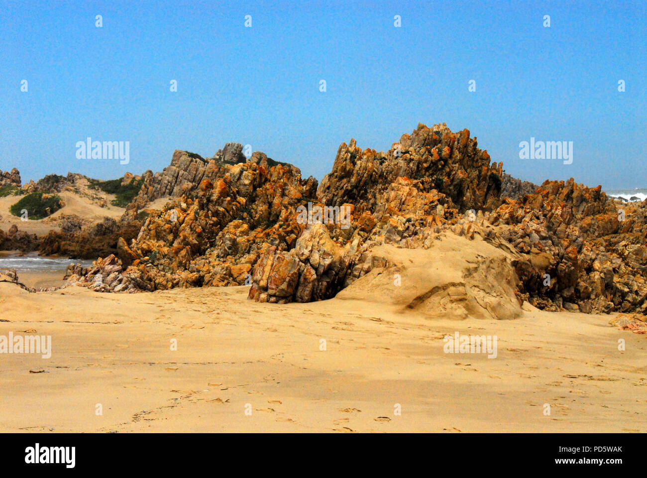 The volcanic rock jutting up on the beach near Knysna, South Africa creates a beautiful background with plenty of space for text. Stock Photo