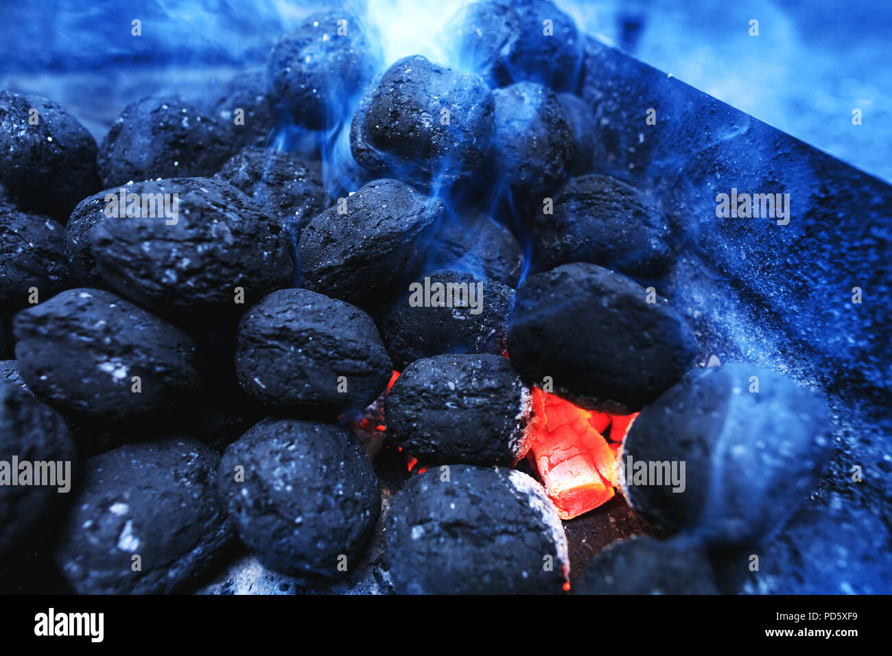 Hot flaming charcoal briquettes glowing in the barbeque grill pit. Real