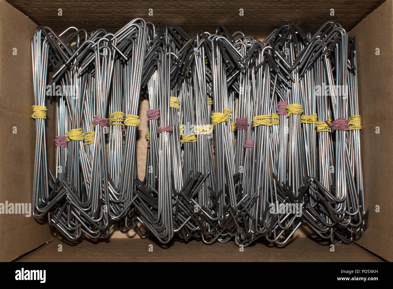 Plenty metal hook hangers in a cardboard box for industrial use like spray painting or coating