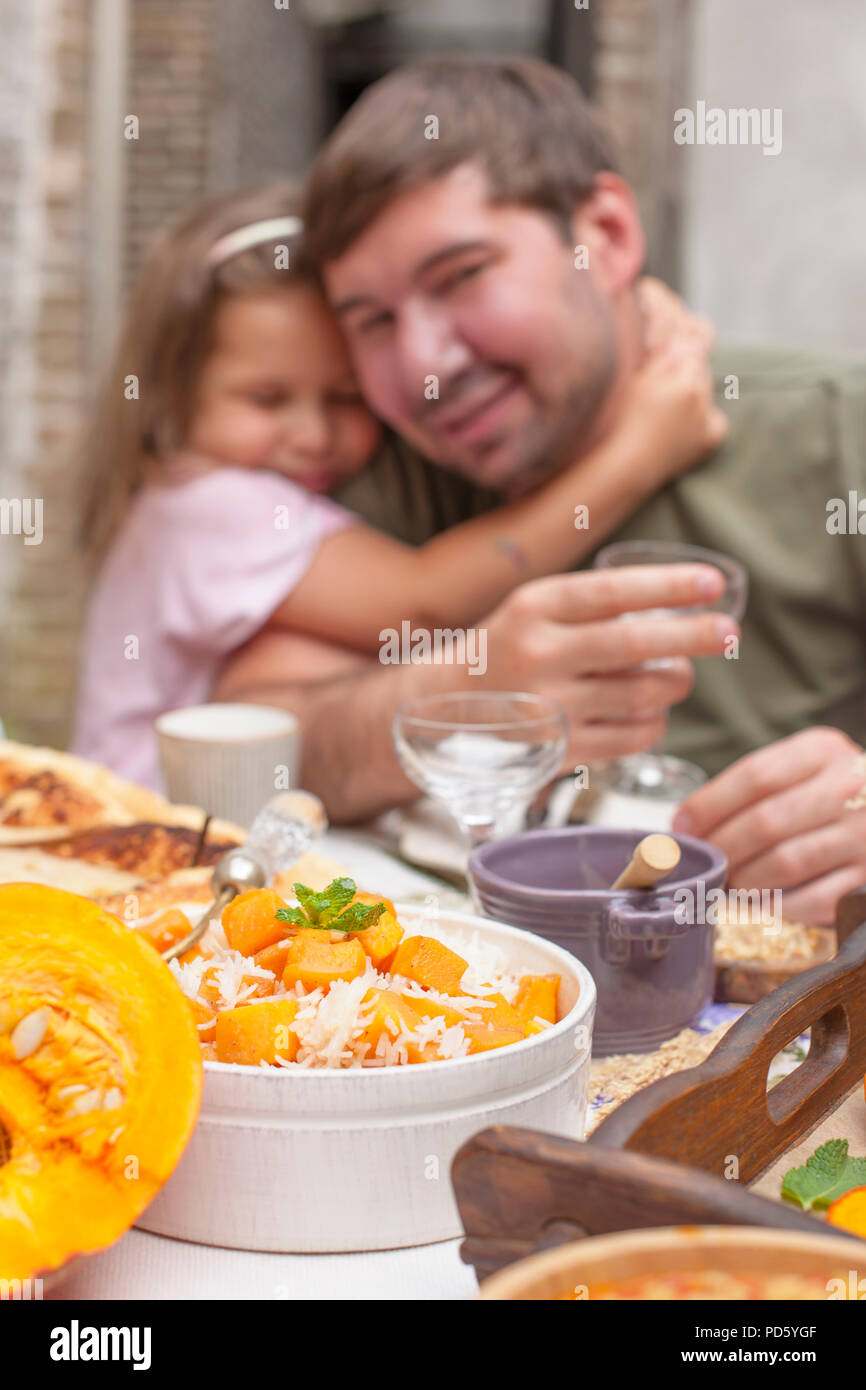 A man with a glass at the dinner table is a little daughter. Family ...