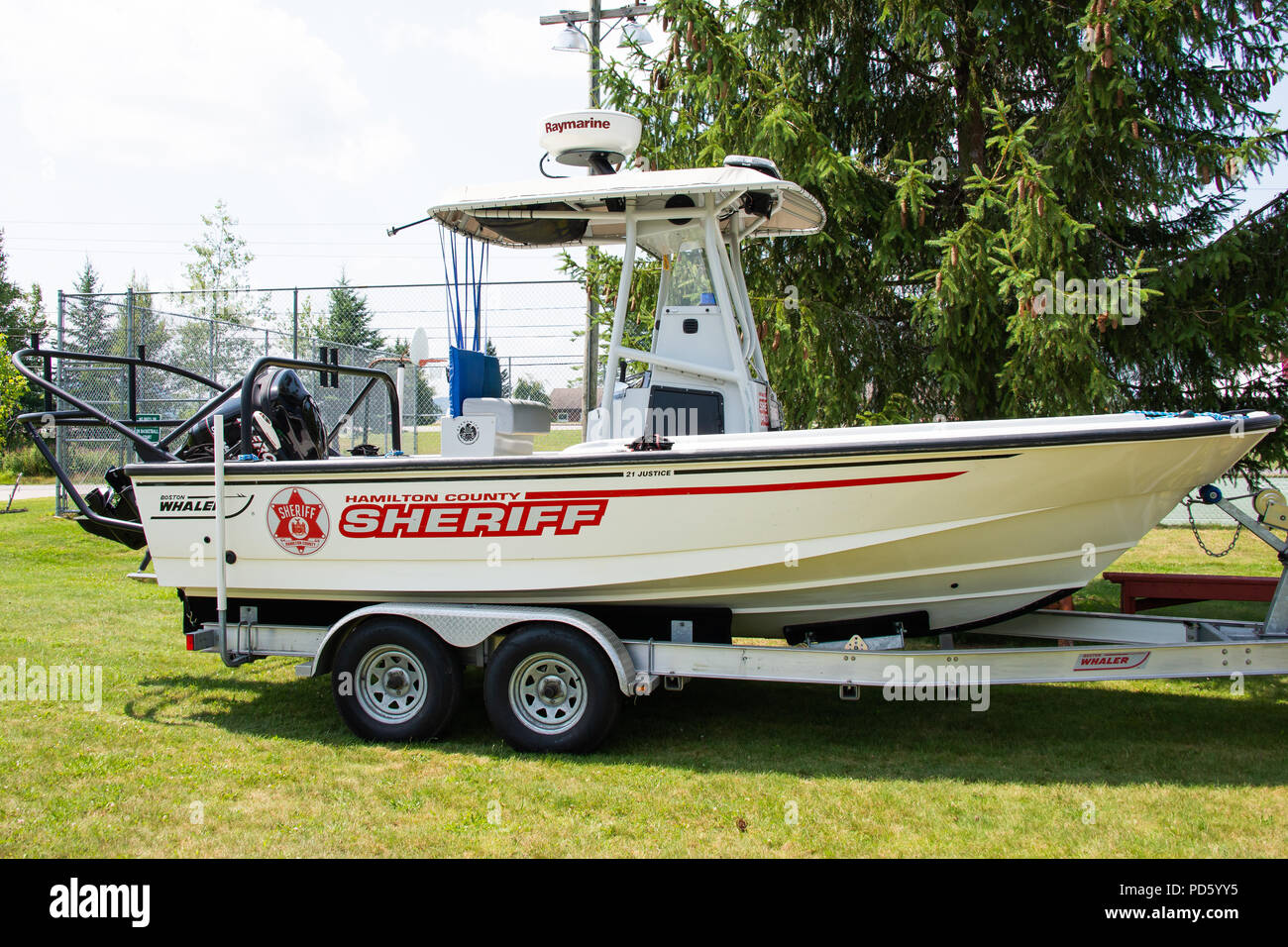 A 21' Justice model of the Boston Whaler set up for police work by the Hamilton County, NY sheriff department sitting on a trailer in a grass field. Stock Photo
