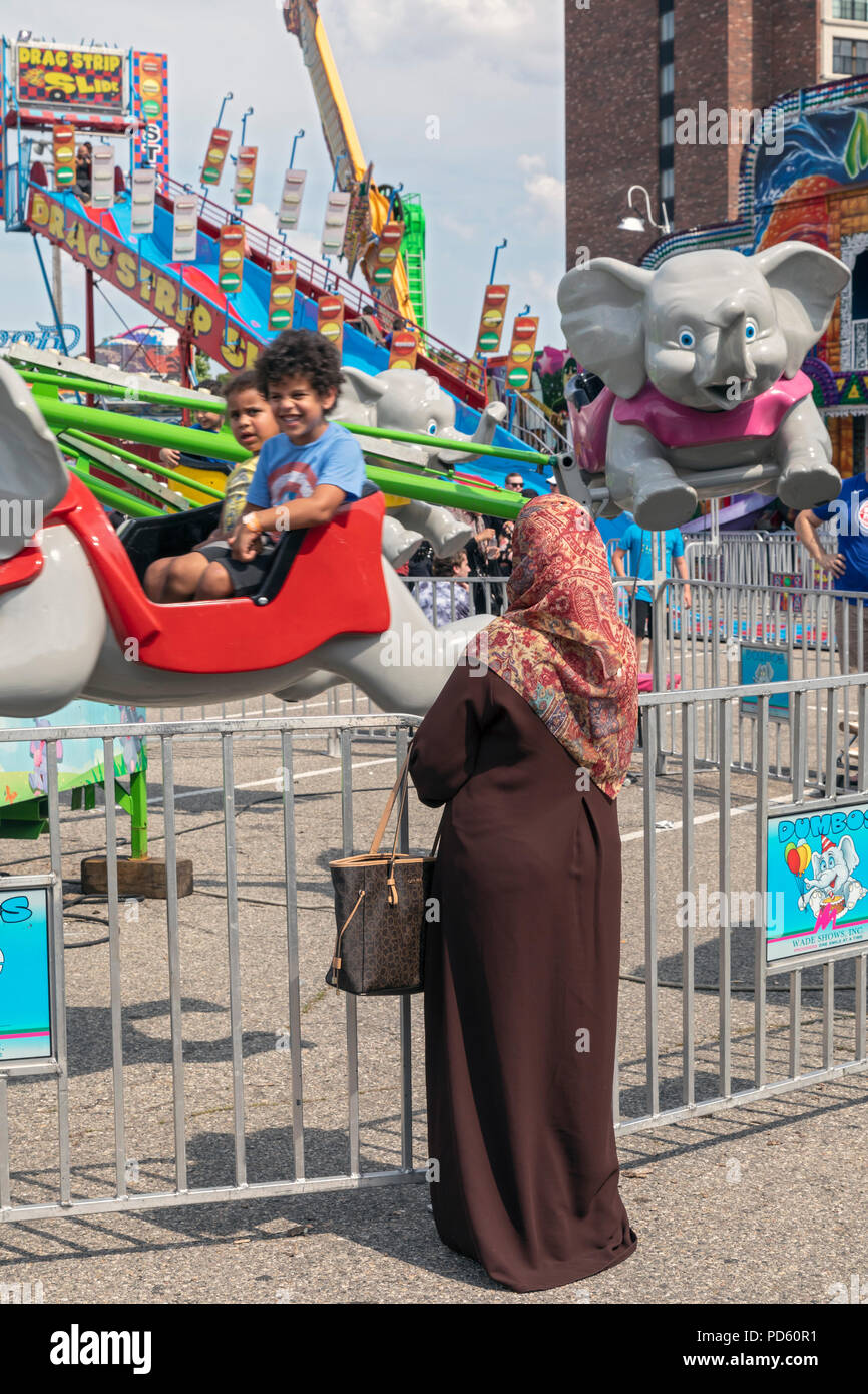 Dearborn, Michigan - An Arab-American woman watches children on a carnival ride at the annual Dearborn homecoming festival. Nearly half of Dearborn's  Stock Photo