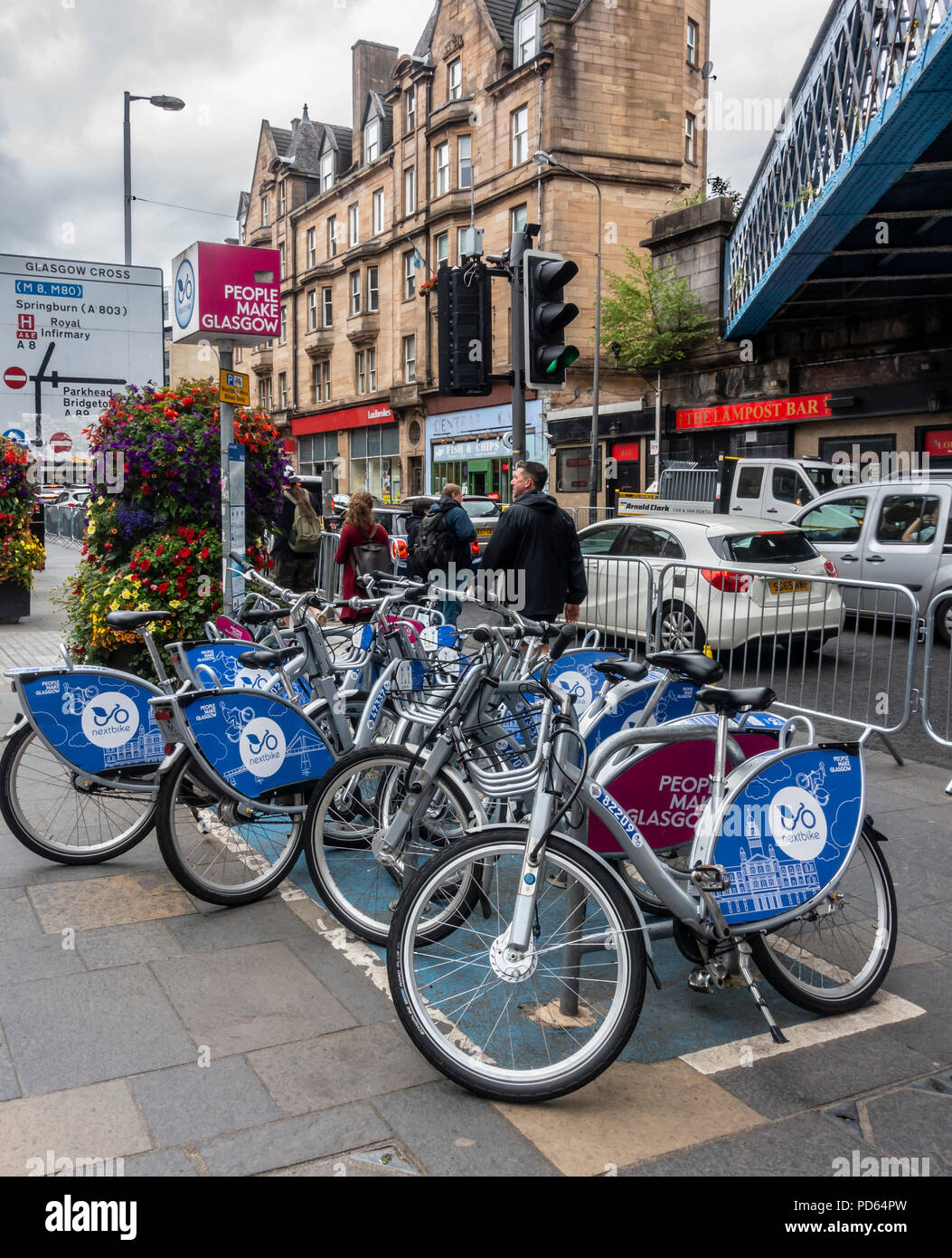 Nextbike bike sharing hire point in Saltmarket, near Glasgow Cross in the East End of Glasgow, Scotland. Large flower planters. Street, direction sign Stock Photo