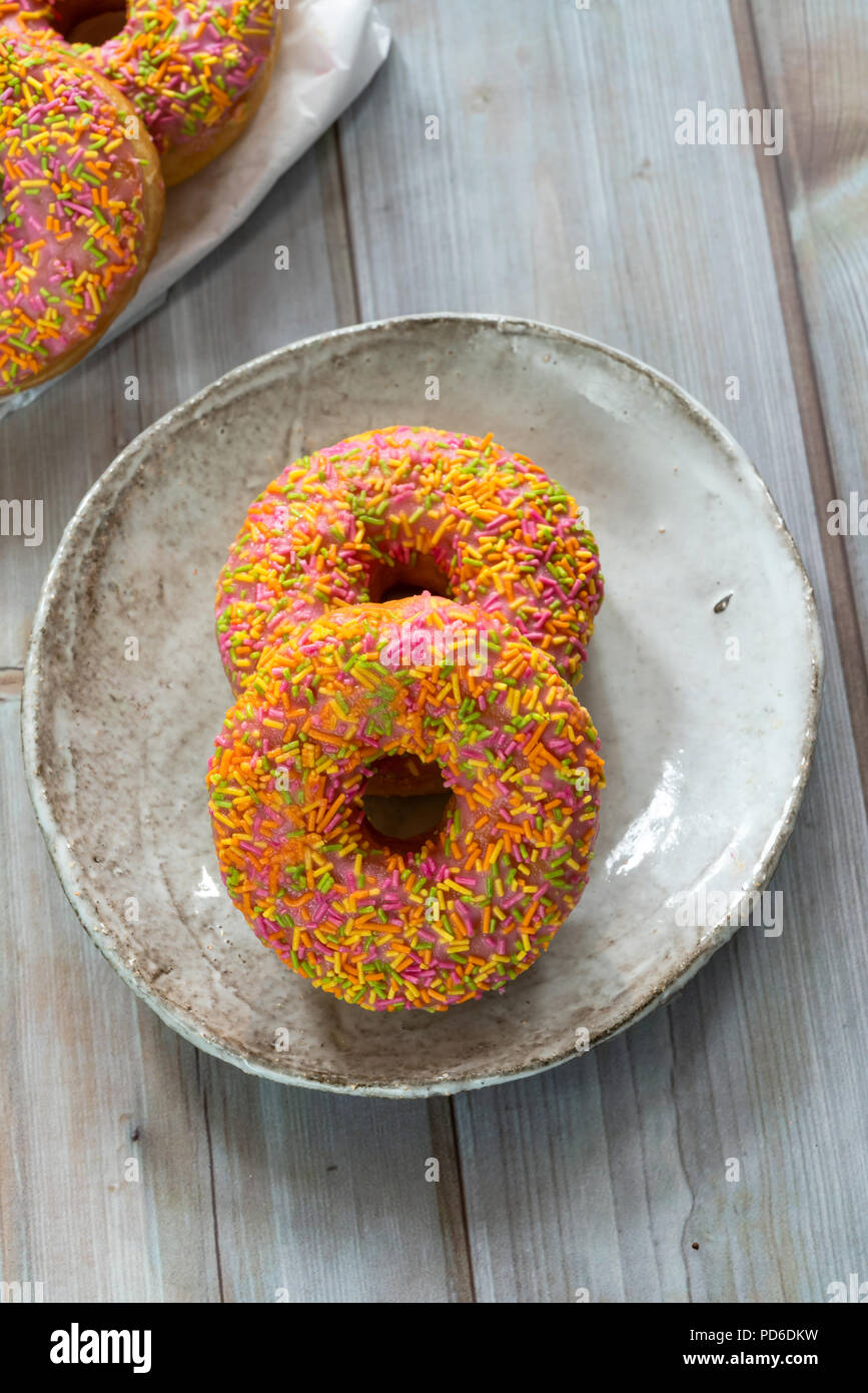 https://c8.alamy.com/comp/PD6DKW/doughnuts-with-colorful-frosting-on-wooden-table-top-view-PD6DKW.jpg