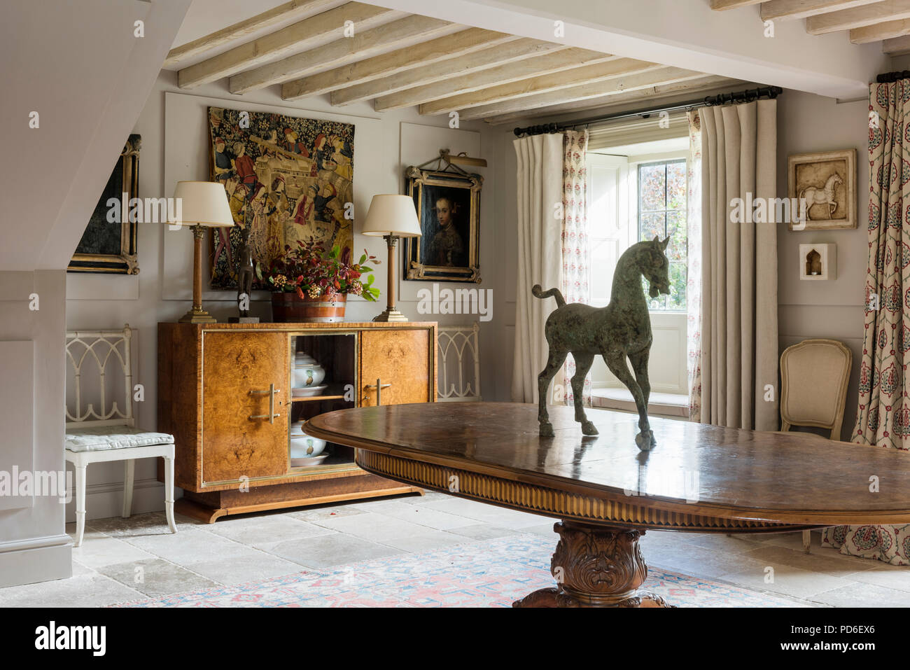 Equestrian statue on oval dining table in entrance hall with lamps on sideboard Stock Photo