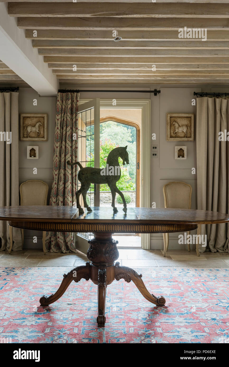 Equestrian statue on oval dining table in entrance hall with open door. Stock Photo