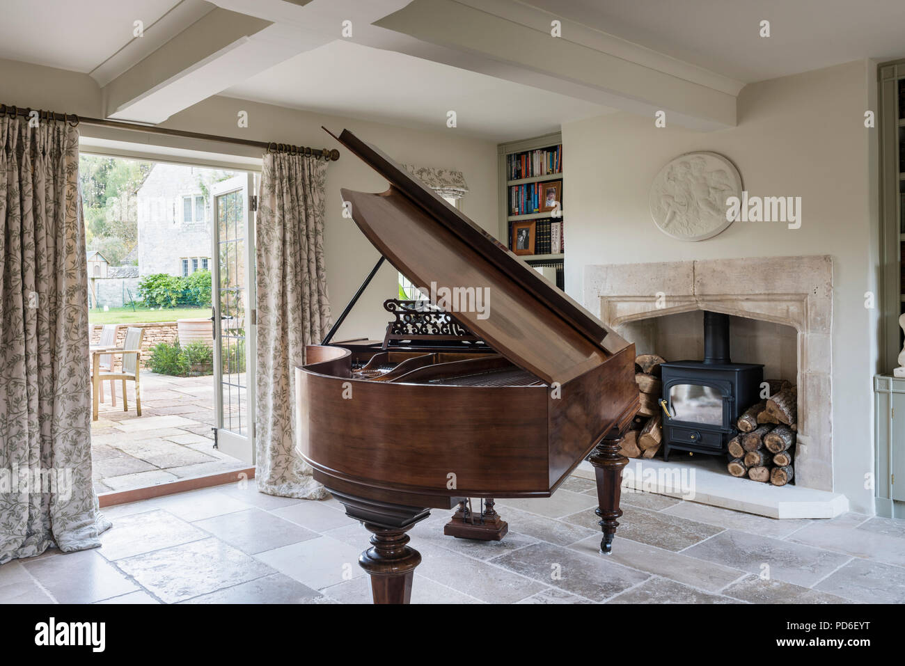 Grand piano and wood burning stove at open doorway. Stock Photo