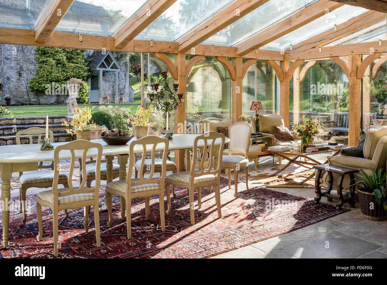 Open plan dining room in glass conservatory extension of 19th century stone farmhouse Stock