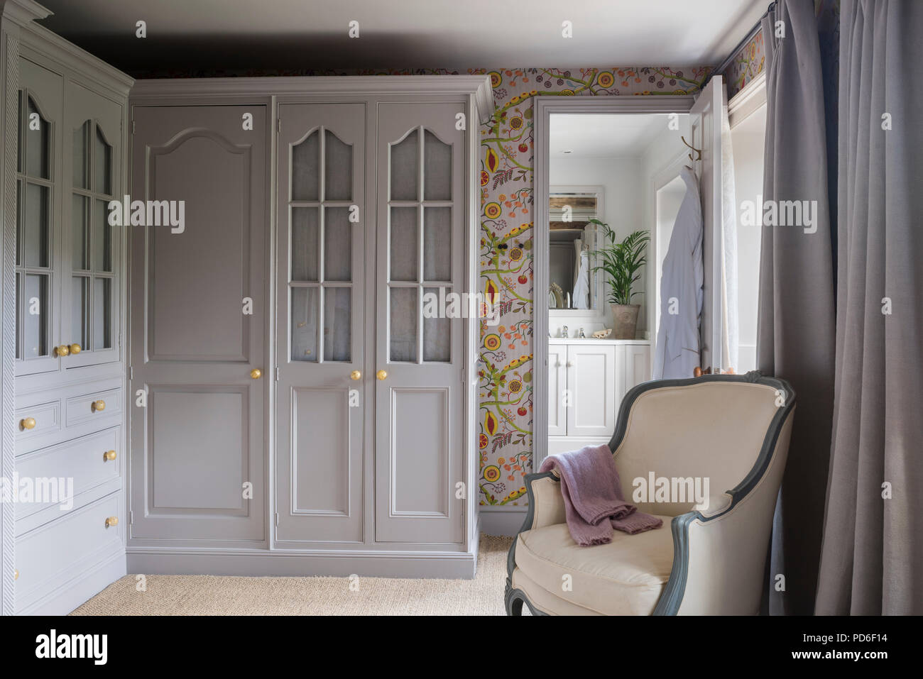Light grey dressing room with ropical wallpaper and view through doorway to ensuite. Stock Photo
