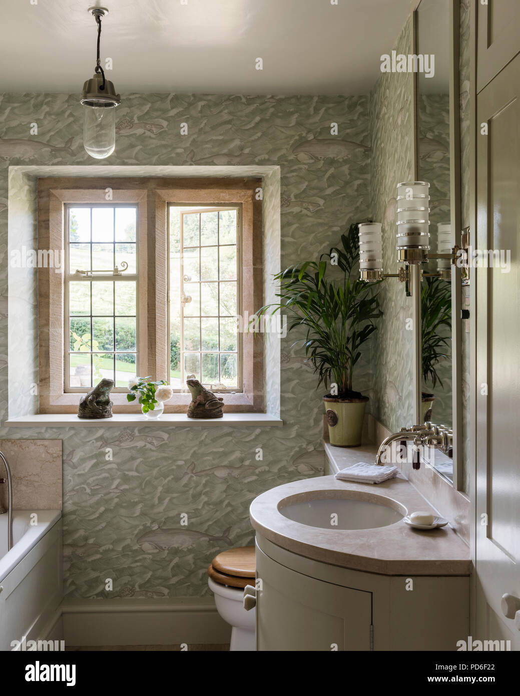 Frog statues on windowsill with mirror over sink. Stock Photo