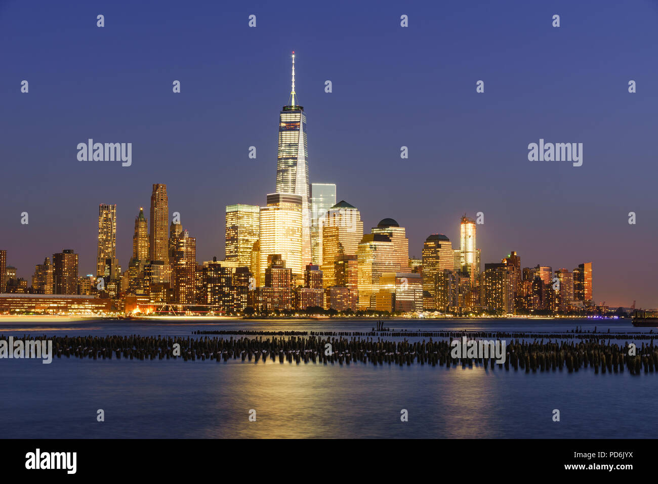 Lower Manhattan skycrapers illuminated at twilight with the Hudson River. Manhattan, New York City Stock Photo