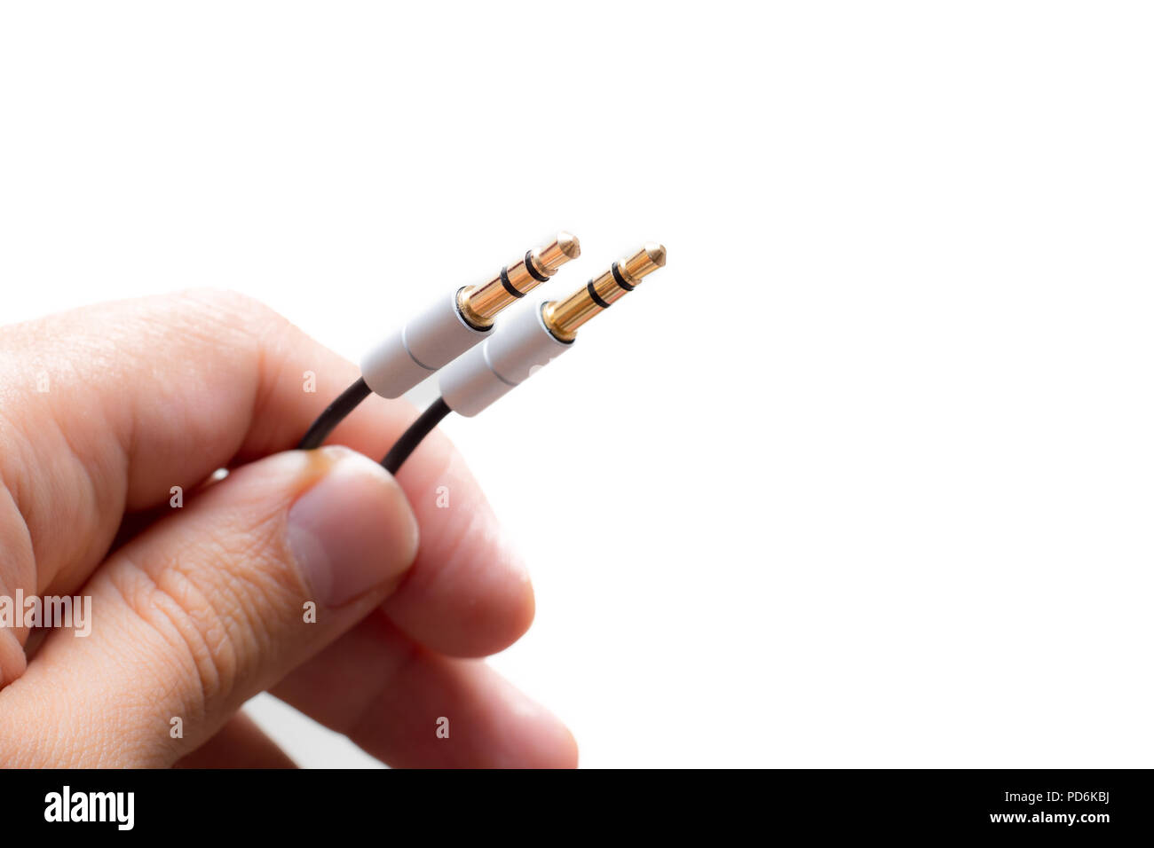 Hand with two stereo audio cable gold coated isolated on white backgrounds Stock Photo