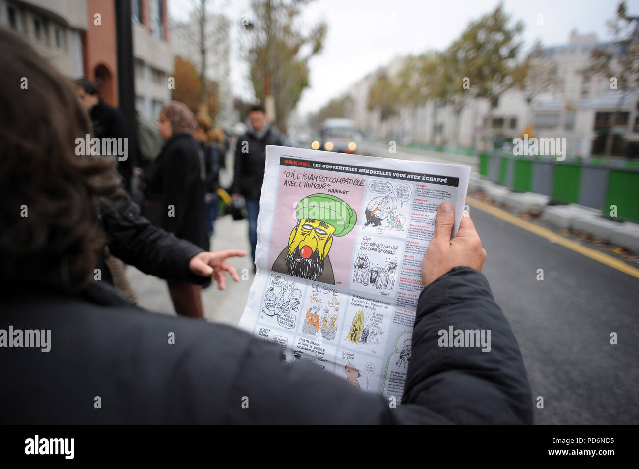 November 2, 2011 - Paris, France: People pick up copies of Charlie Hebdo's special 'Sharia Hebdo' edition in front of the office of French satirical weekly paper Charlie Hebdo after an overnight petrol bomb attack. The paper was targeted after publishing a caricature of prophet Muhammad on its front cover for a special issue entitled 'Shariah Hebdo'. Des gens ramassent et lisent le numero de 'Charia Hebdo' devant les locaux de Charlie Hebdo apres qu'une attaque au cocktail molotov a declenche un incendie et detruit les locaux boulevard Davout de l'hebdomadaire satirique. Cette attaque fait sui Stock Photo