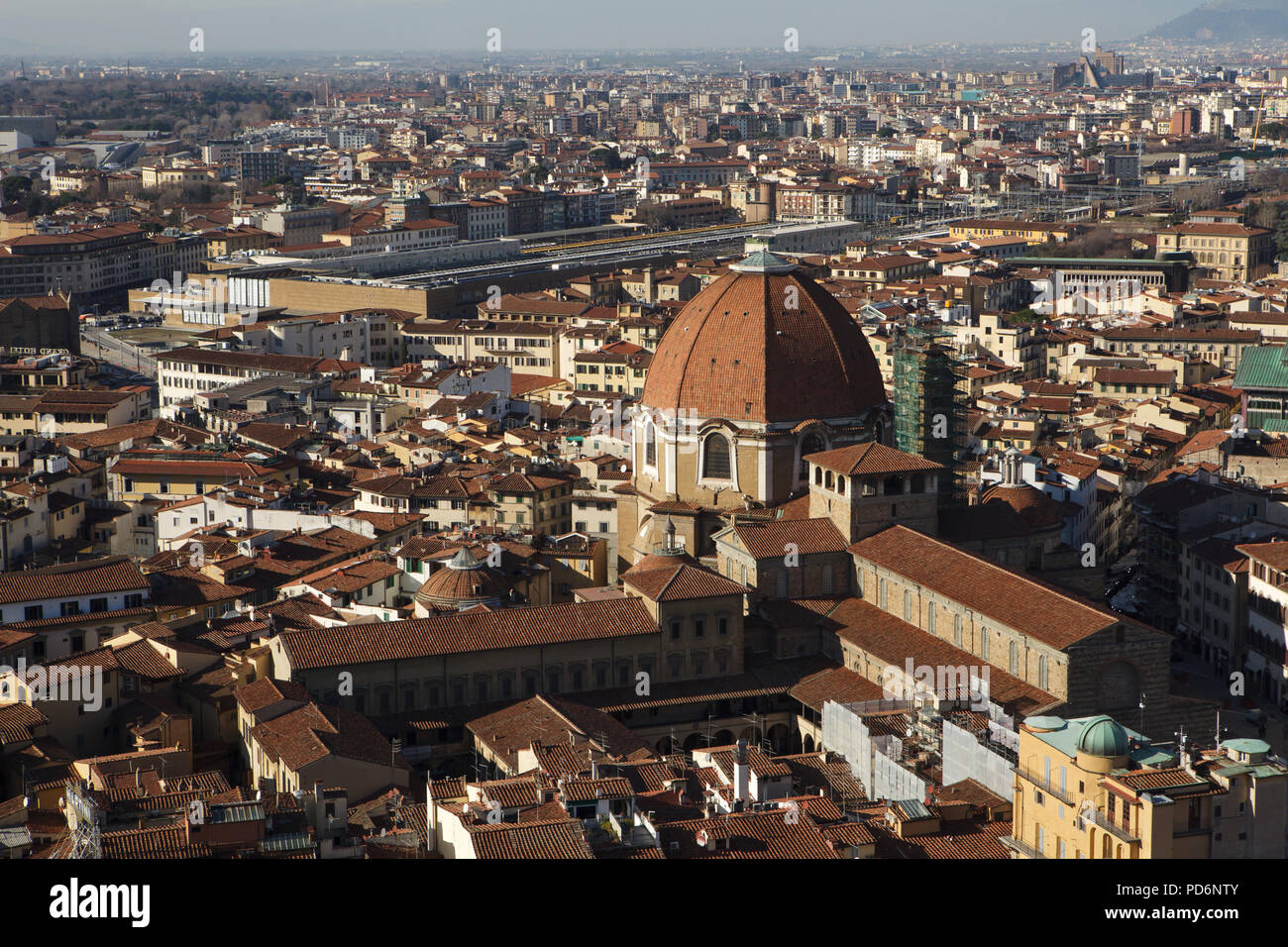 Basilica di San Lorenzo (Basilica of St Lawrence) and the dome of the Cappella dei Principi (Chapel of the Princes) rising over the tiled roofs of the Florence downtown pictured from the dome of the Florence Cathedral (Duomo di Firenze) in Florence, Tuscany, Italy. Santa Maria Novella railway station is seen in the background. The Laurentian Library (Biblioteca Medicea Laurenziana) is seen in the foreground left from the dome and the basilica. Stock Photo