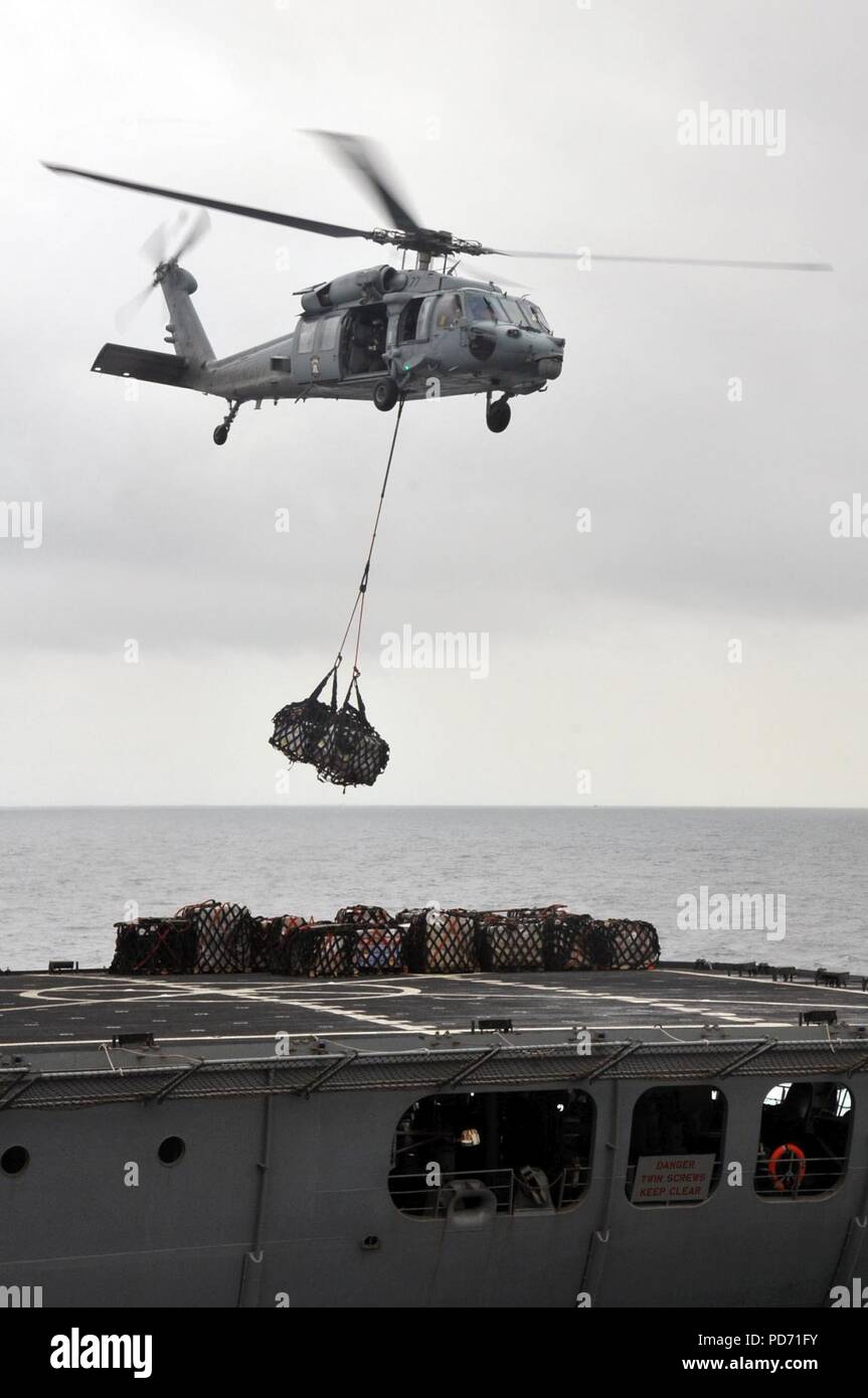 An MH-60 Seahawk helicopter transfer supplies from the fleet replenishment oiler USNS Rappahannock (T-AO 204) to the amphibious assault ship USS Boxer (LHD 4) during a replenishment at sea operation in Stock Photo