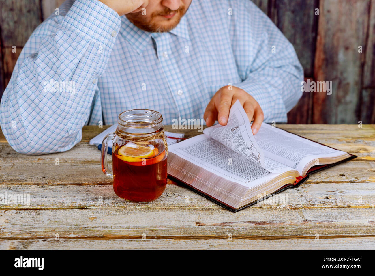 A middle aged man sitting at a table reading the Bible Stock Photo