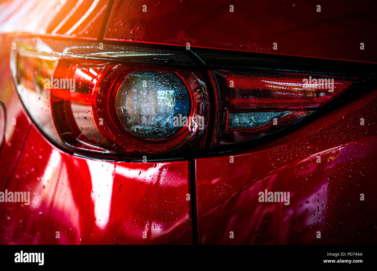 Red compact SUV car with sport and modern design are washing with water. Car care service business concept. Car covered with drops of water after clea Stock Photo