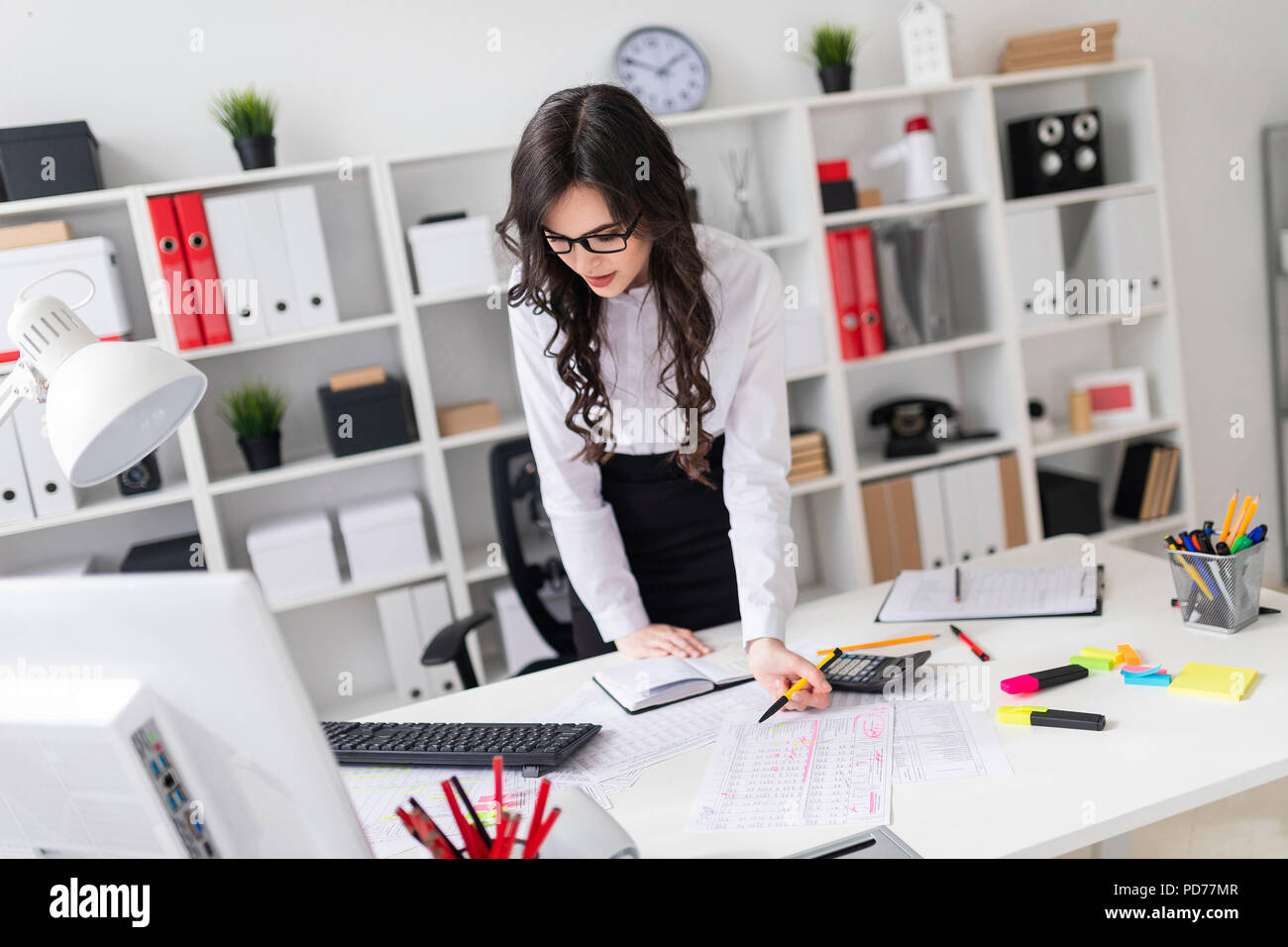 A Beautiful Young Girl Stands Bent Over An Office Desk Holds A