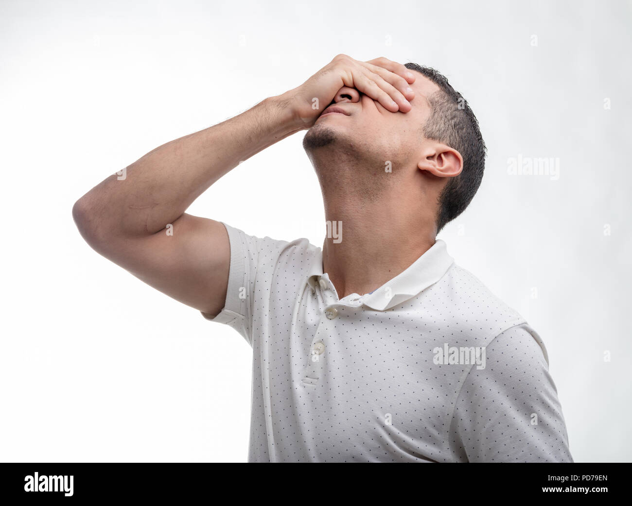 Man covering his face with his hand as he tilts back his head in a conceptual image of despair, sorrow, forgetfulness or hopelessness on white Stock Photo