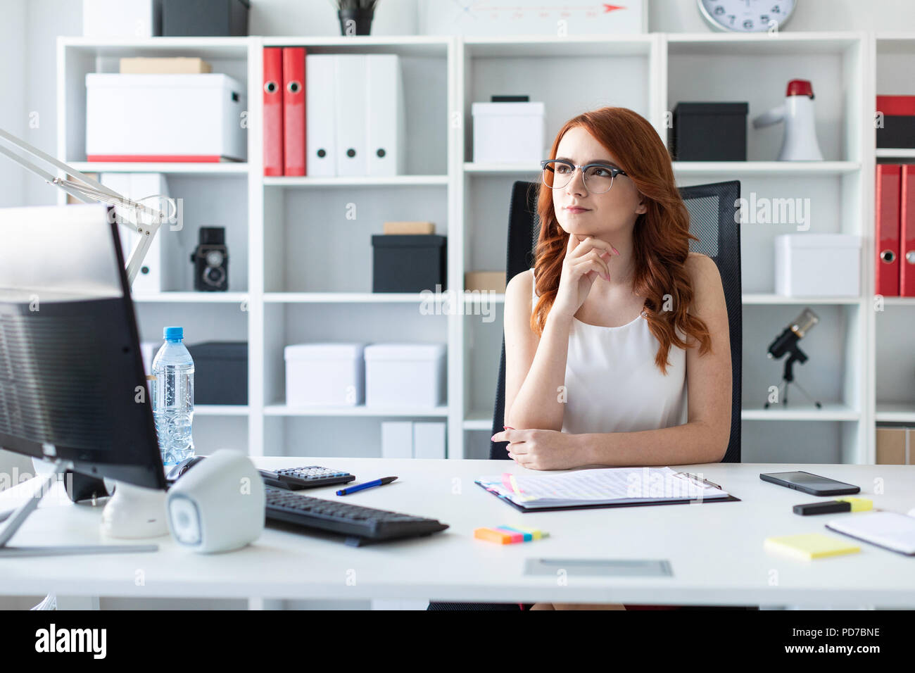 Beautiful young girl is sitting at the desk in the office. Stock Photo