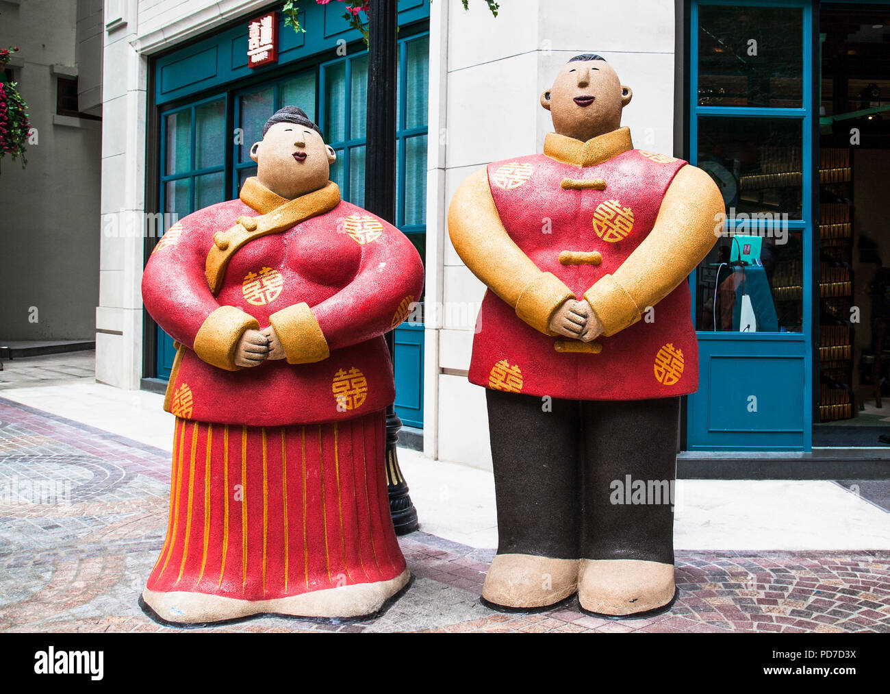 HONG KONG; CHINA - APRIL 3, 2016: Two statues of Chinese and Chinese waiter in red costume in front of entrance to restaurant on Apr 3, 2016 in Hong K Stock Photo