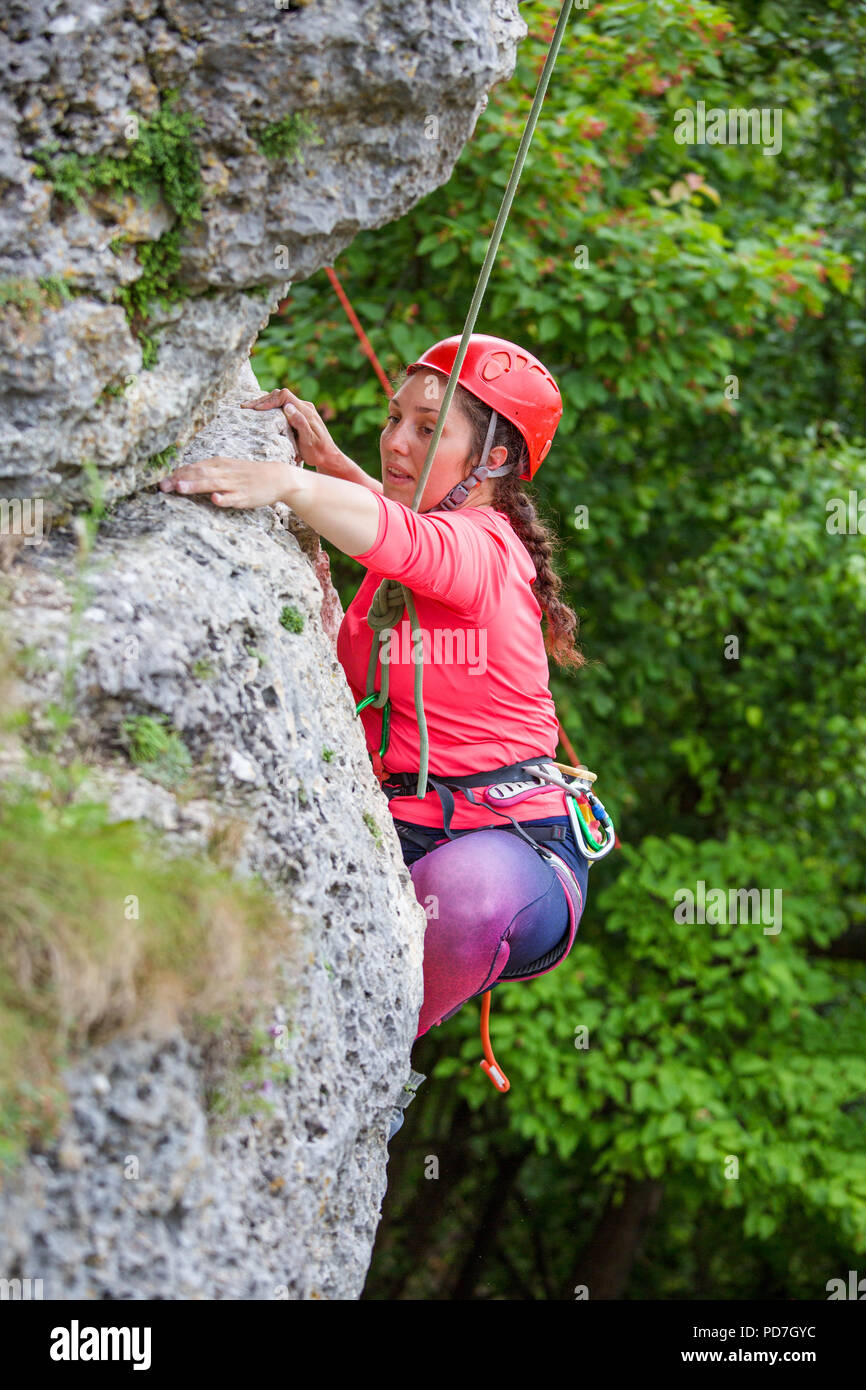 Photo of sporty woman in red helmet clambering over rock against ...