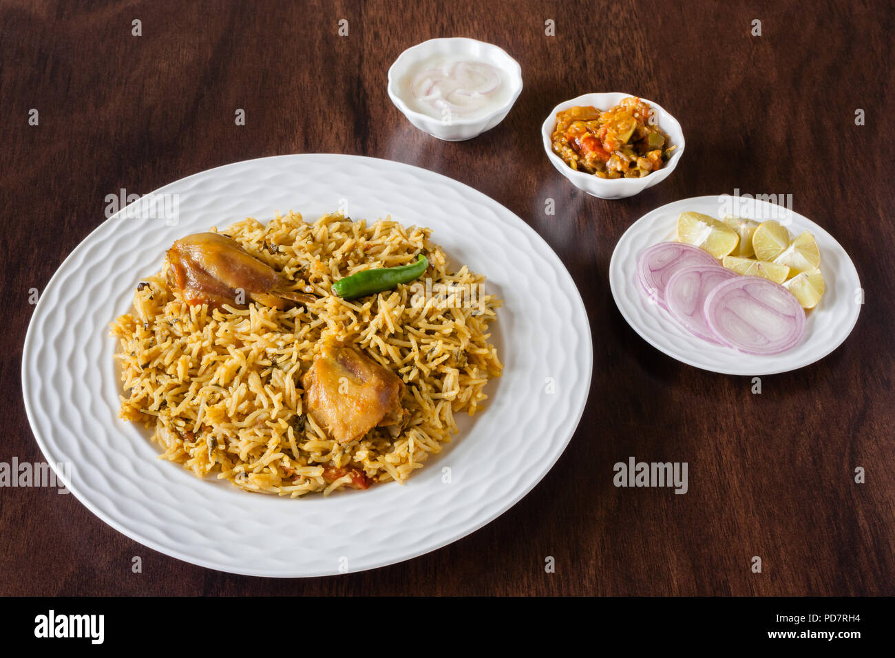 Overhead view from the top of delicious Indian chicken biryani served with traditional sides, salad (raita) and gravy. Natural light used. Stock Photo