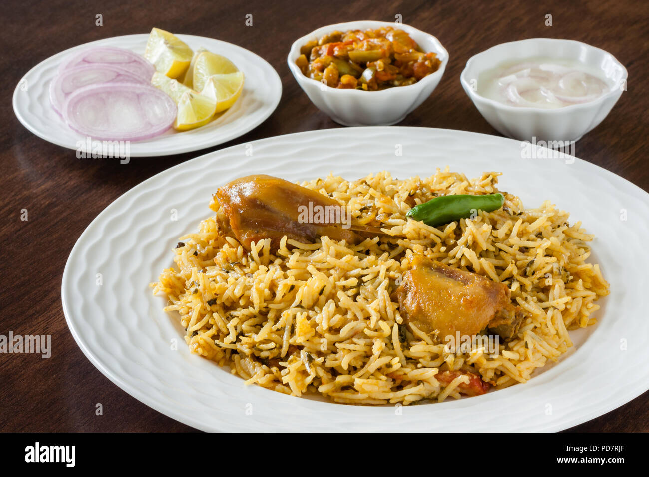 Closeup view from the top of delicious Indian chicken biryani served with traditional sides, salad (raita) and gravy. Natural light used. Stock Photo