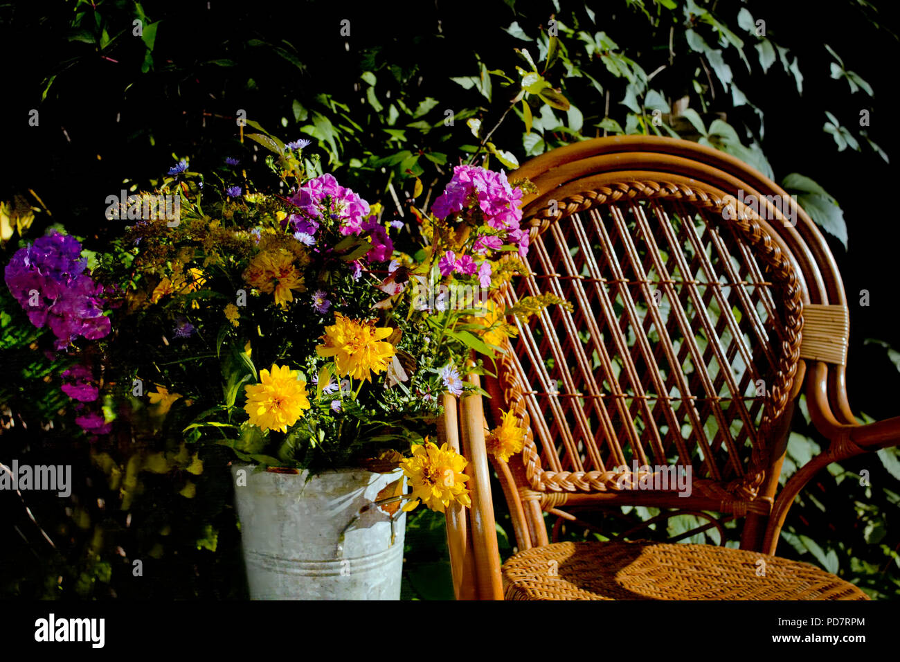 Wicker Chair And A Floor Vase With Flowers In An Autumn Garden