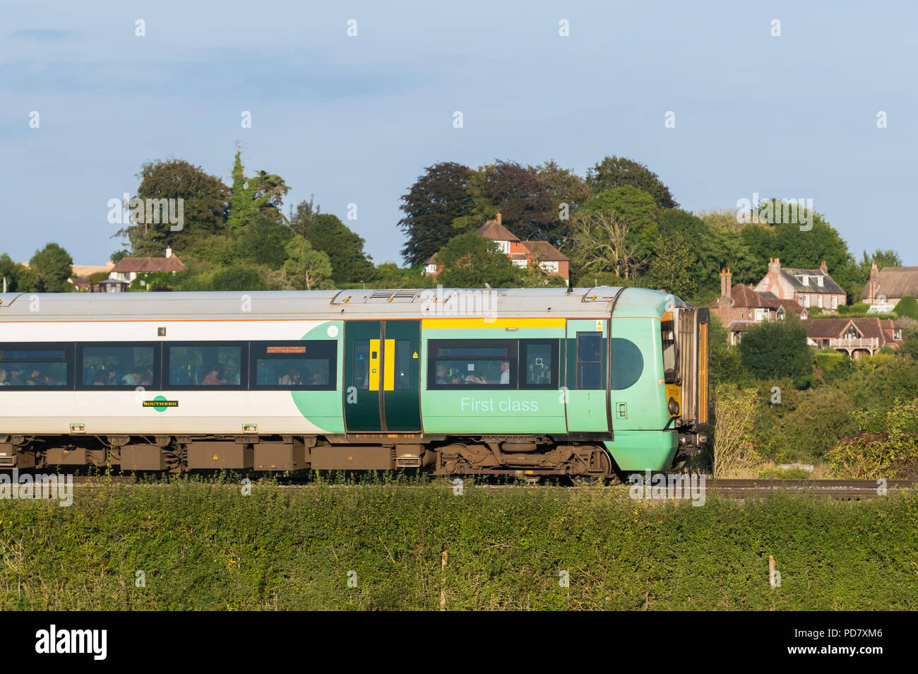 British Southern Rail Class 377 Electrostar train travelling through the countryside in evening light through the South Downs in West Sussex, UK. Stock Photo