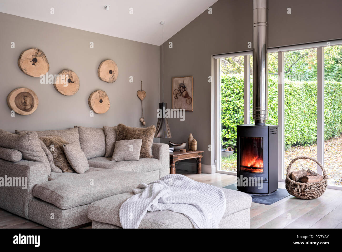 Large Linea sofa and foot stool in open plan living space with woodburning stove Stock Photo