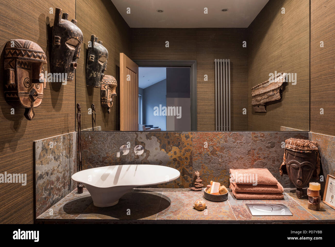 African masks and Brazilian slate in cloakroom with walls bedecked in Foja grass cloth from Brian Yates Stock Photo