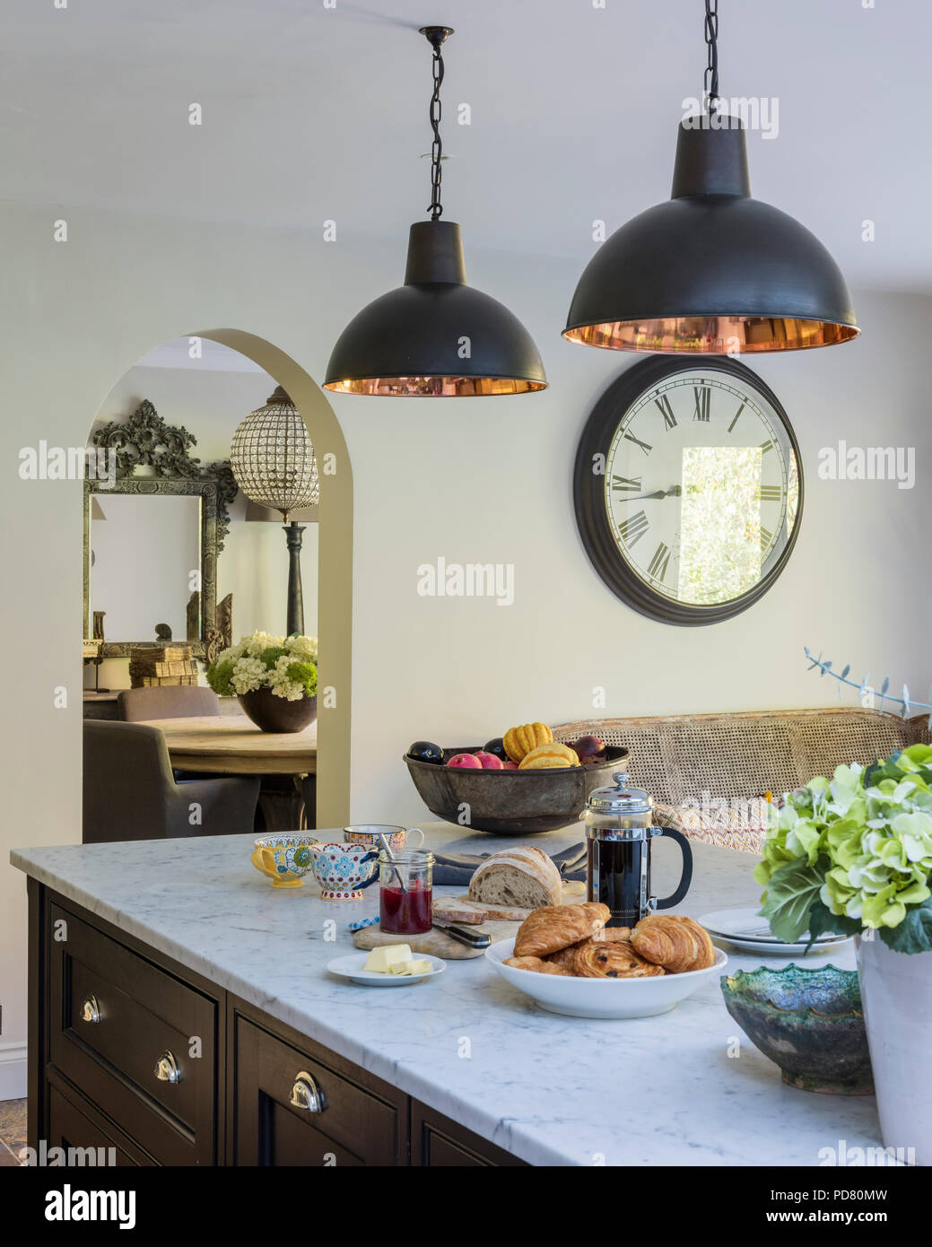 Bespoke kitchen island by Thomas Ford & Sons is painted in Tanner's Brown by Farrow & Ball. Industrial style pendant lights hang above the marble work Stock Photo