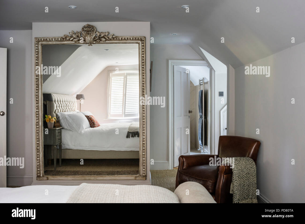 Leather armchair and oversized mirror  in bedroom with Pentlow buttoned double bed from Sofas & Stuff Stock Photo