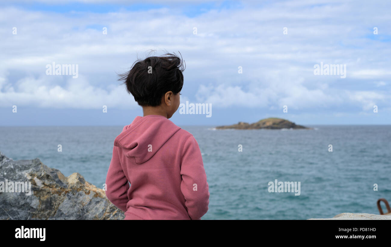 Kid looking at sea. Child looking at water. Concept of kid thinking or lonely child. Stock Photo