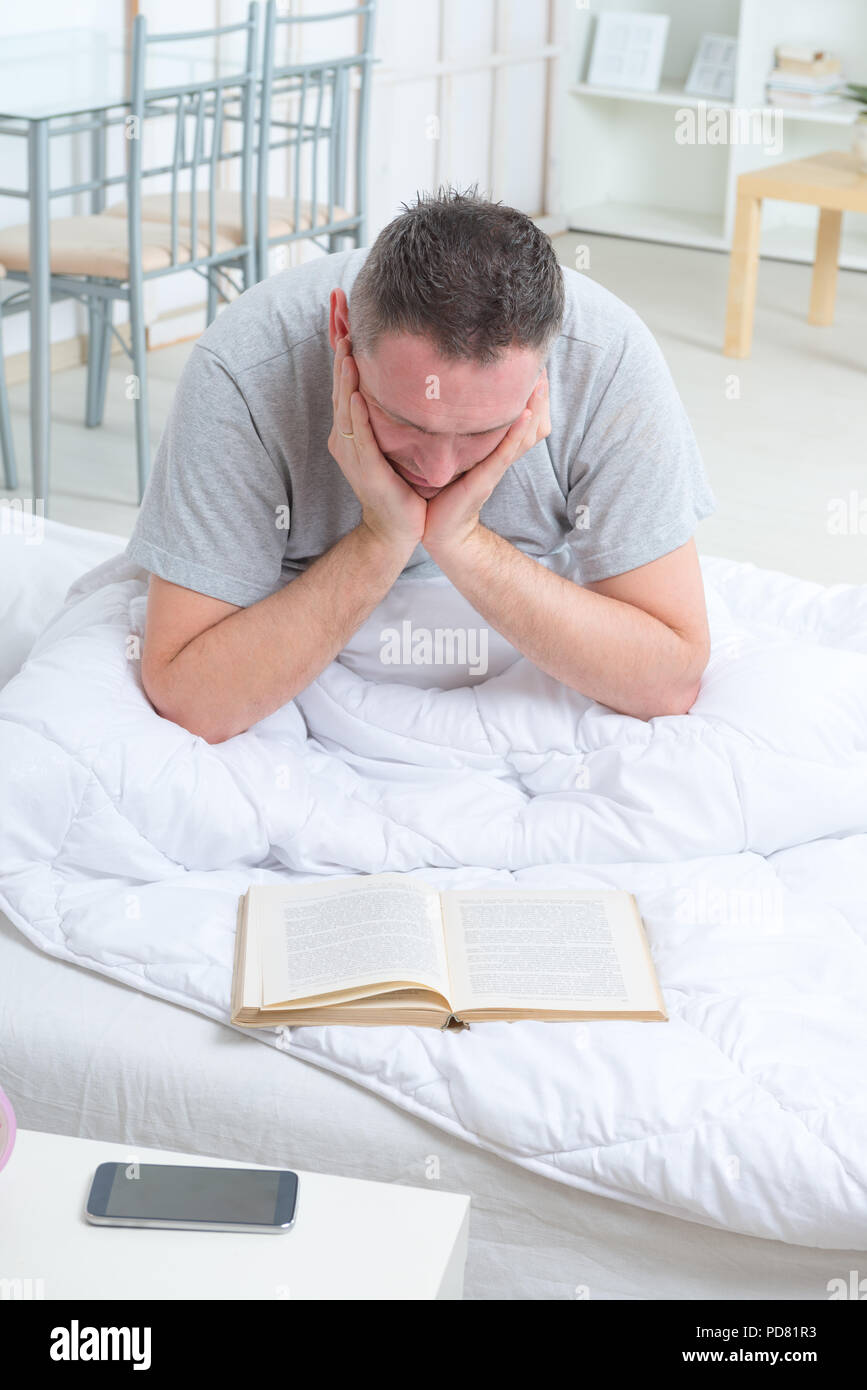Man reading book in bed Stock Photo - Alamy