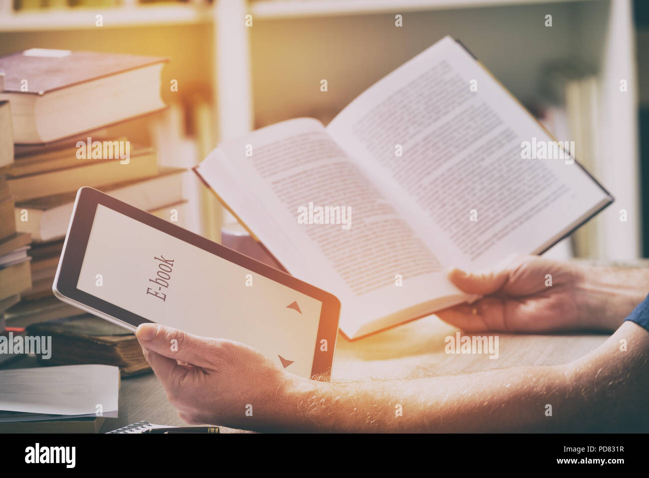 Man sitting in a library and holding in hands a modern ebook reader and